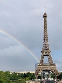 Low angle view of eiffel tower with rainbow against cloudy sky