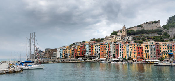 Sailboats moored in sea against buildings in city