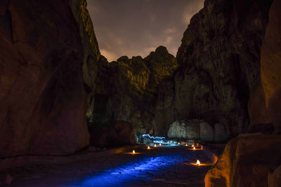 Scenic view of illuminated cave against sky at night