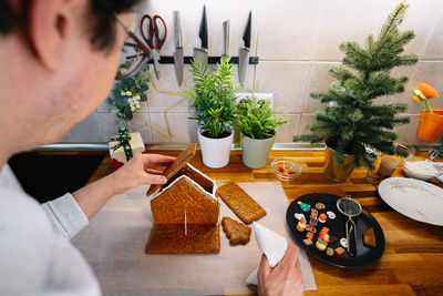 Midsection of man holding christmas tree on table