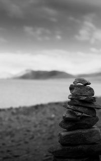 Stack of stones in sea against sky