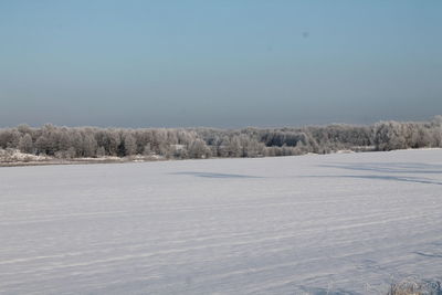 Snow covered landscape against clear sky