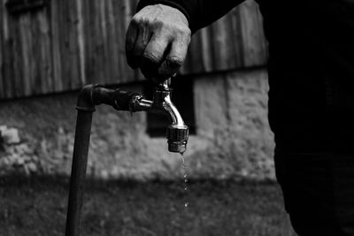 Midsection of man holding faucet outdoors