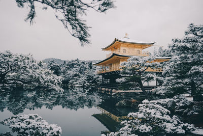 Traditional building by lake against sky