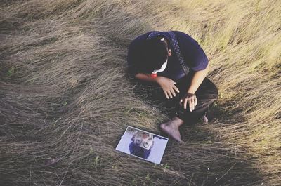 High angle view of young man using digital tablet sitting on field