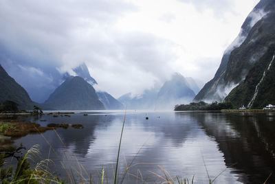 Scenic view of lake by mountains against sky, milford sound