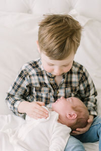 Big brother hold baby sister for first time on bed