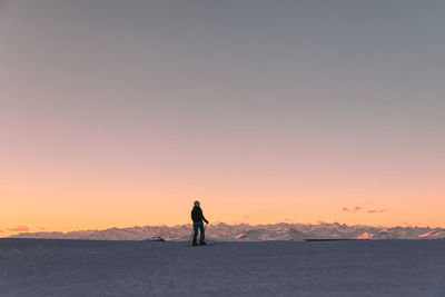 Female skier looking at snowcapped rugged mountains in dolomiti superski resort, italy during sunset