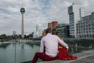 Rear view of woman looking at cityscape against sky