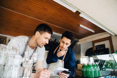 Male coworkers looking at order while standing in commercial land vehicle