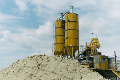 Low angle view of yellow factory against sky