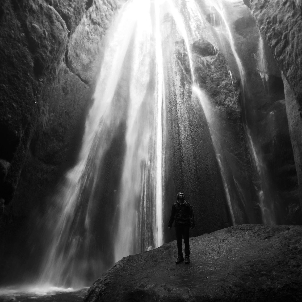 lifestyles, motion, leisure activity, men, waterfall, long exposure, rock - object, rear view, standing, person, water, rock formation, full length, cave, blurred motion, flowing water, travel, tourism