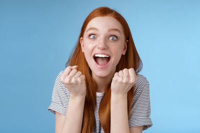 Portrait of young woman against blue background