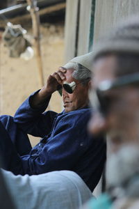 Midsection of man holding camera while sitting outdoors