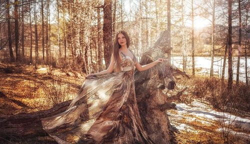 Beautiful woman wearing dress while standing against trees at forest