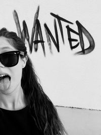 Portrait of woman with mouth open wearing sunglasses against wall