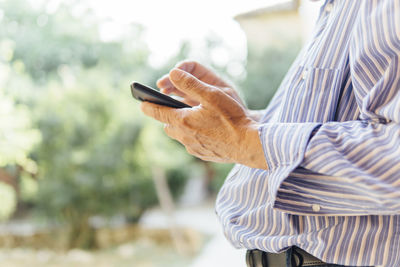 Midsection of man using mobile phone