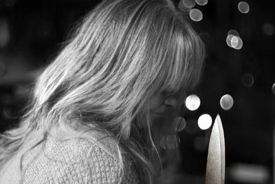 Close-up portrait of woman with illuminated hair at night