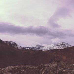 Scenic view of snow covered mountains against cloudy sky