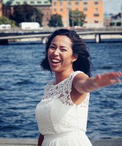 Portrait of smiling young woman standing against sea