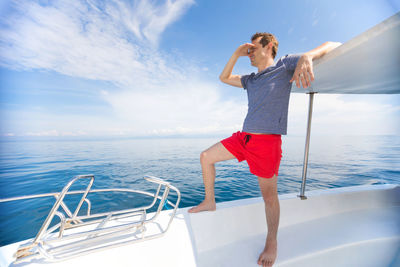 Full length of young woman standing by sea against sky