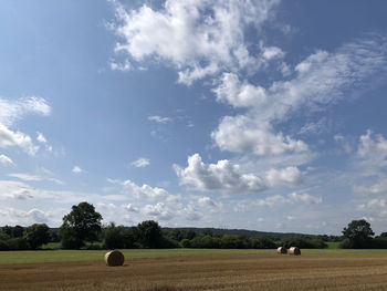 Hay bales on field against sky