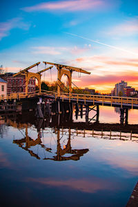 Bridge over river against sky during sunset