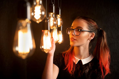 Portrait of woman holding illuminated light bulb