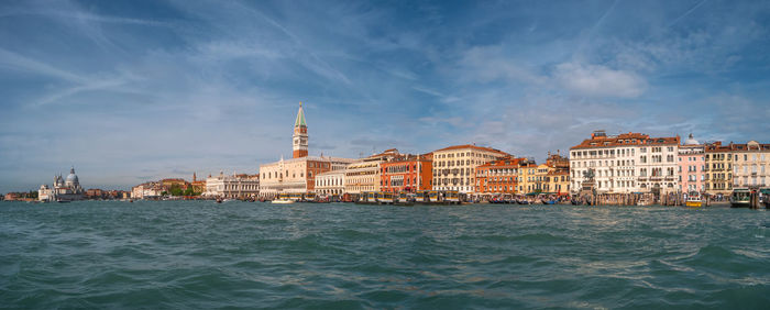 View of buildings by sea against cloudy sky