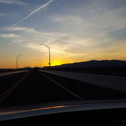 Road by silhouette landscape against sky during sunset