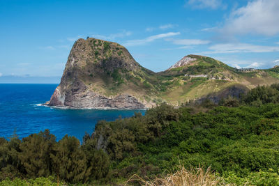 Scenic view of sea by mountain against sky