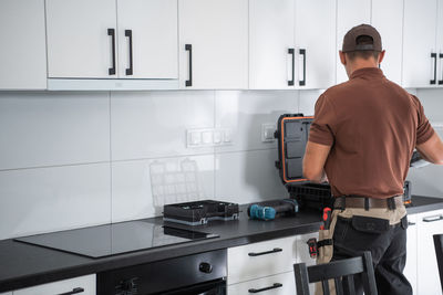 Rear view of repairman working at kitchen counter