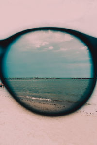 Close-up of sea against sky seen through glass