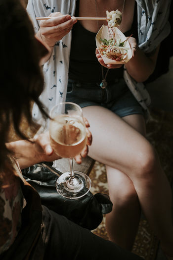 Midsection of female friends having food and drink at home