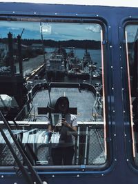 Reflection of man on mirror against sky in city