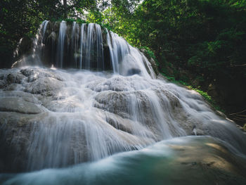 Scenic waterfall smooth stream in rainforest. bottom up angle. erawan falls, kanchanaburi, thailand.