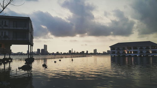 Scenic view of river by cityscape against sky