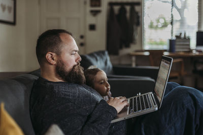 Close up of dad working from home with young daughter