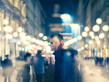 Portrait of young man in city at night