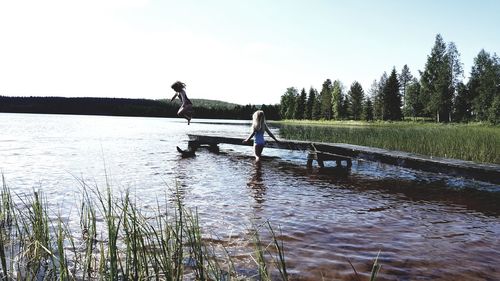 Friends enjoying by lake against clear sky