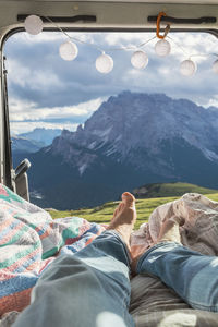 Man relaxing in campervan against mountain range, sesto dolomites, dolomites, alto adige, italy
