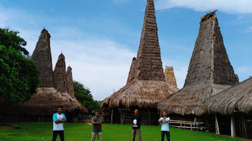 Rear view of people walking by historical building against sky