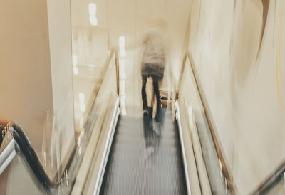 High angle view of woman walking on escalator in building