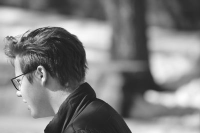 Side view of teenage boy wearing eyeglasses outdoors