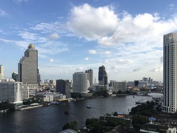 City buildings by river against sky