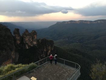 Rear view of man standing on mountain against sky