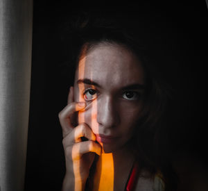 Close-up portrait of young woman making face in darkroom