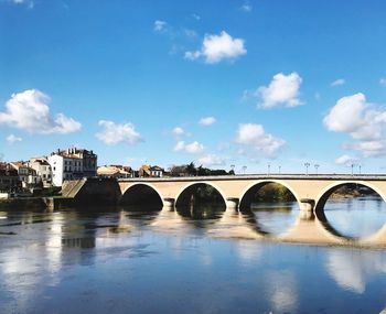 Arch bridge over river against sky