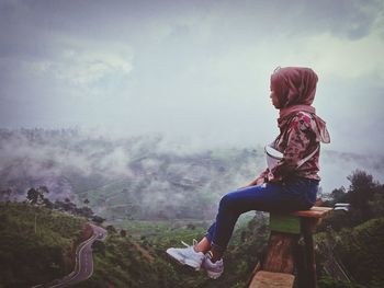Rear view of woman sitting on mountain