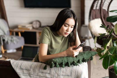 Young woman using mobile phone at home